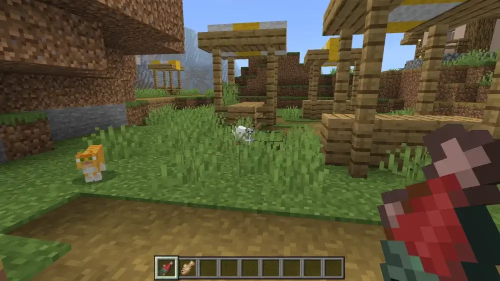 Player holding raw salmon near two cats in a Minecraft village