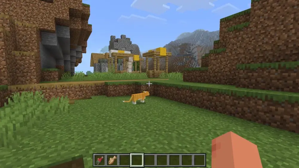 Stray orange cat near a mountain village in Minecraft
